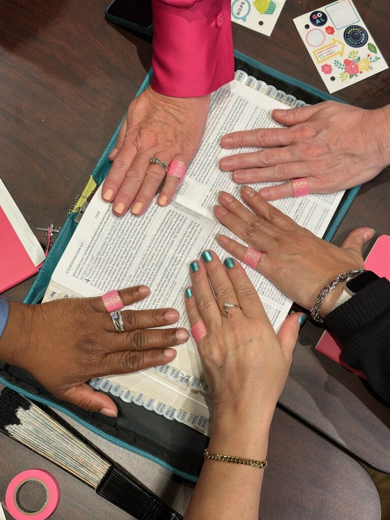 Hands gathered around Scripture in Marcy’s supplied study photo